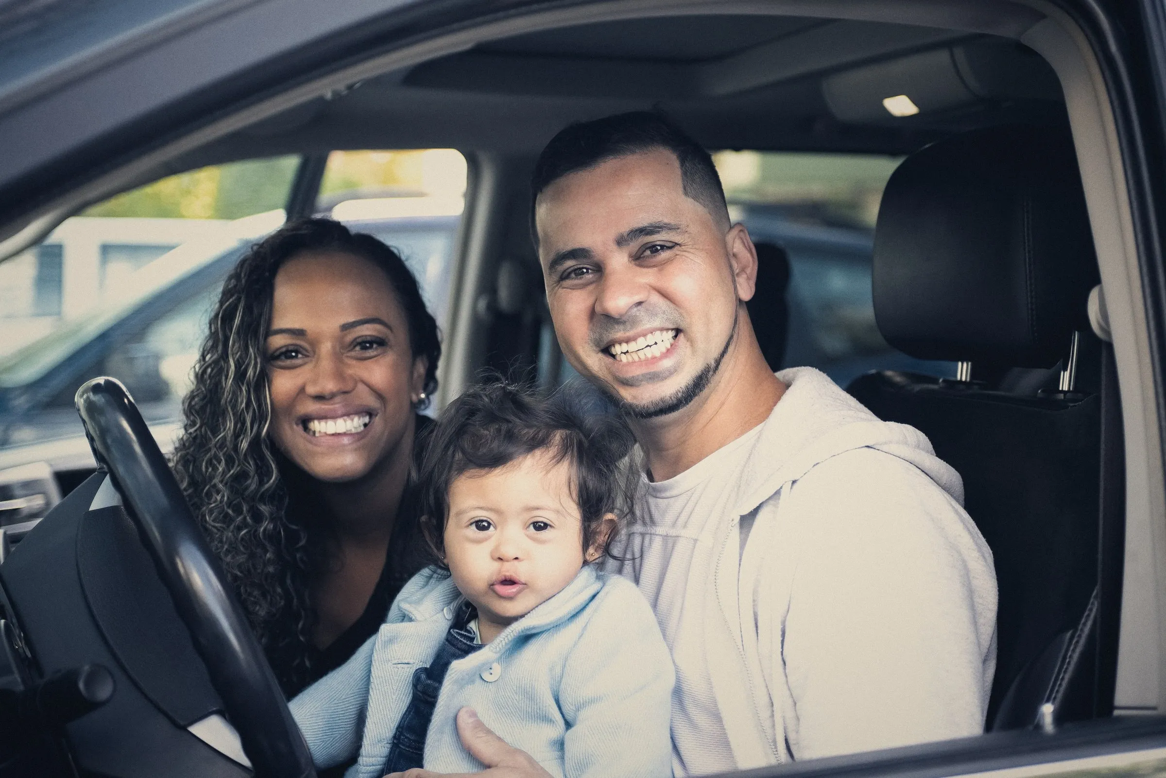 Familia sonriendo dentro de su carro particular