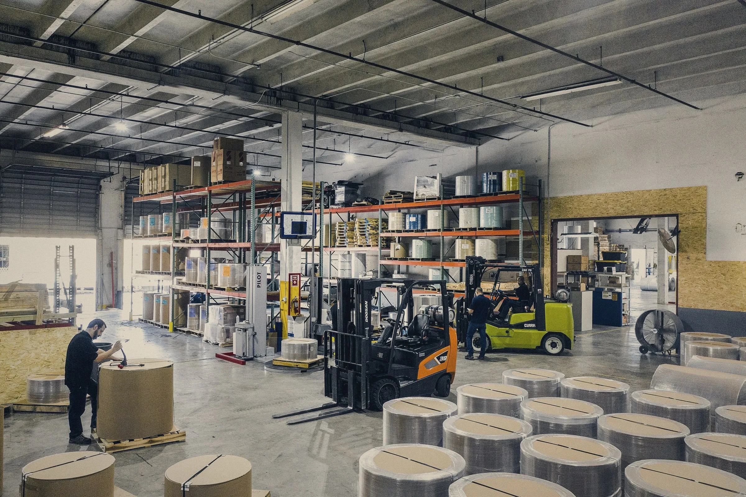 Bodega de una empresa con estanterías, mercancía y montacargas