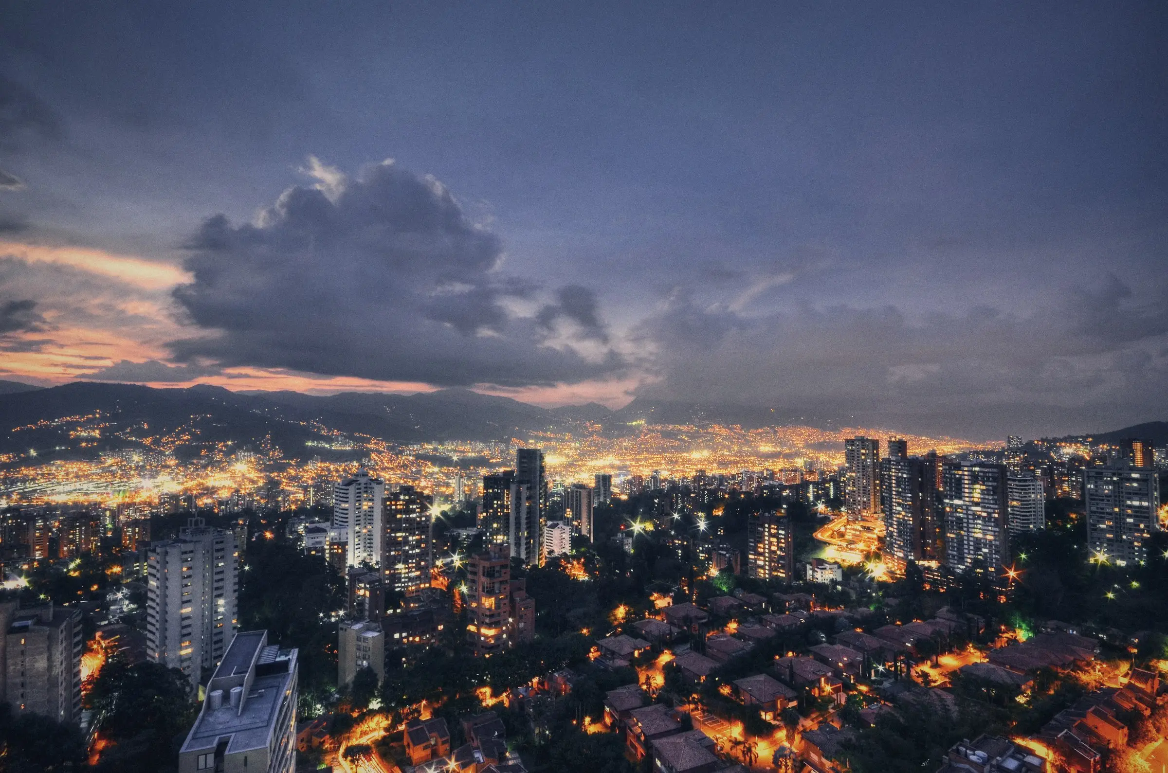 Ciudad colombiana al atardecer con las luces encendidas entre las montañas