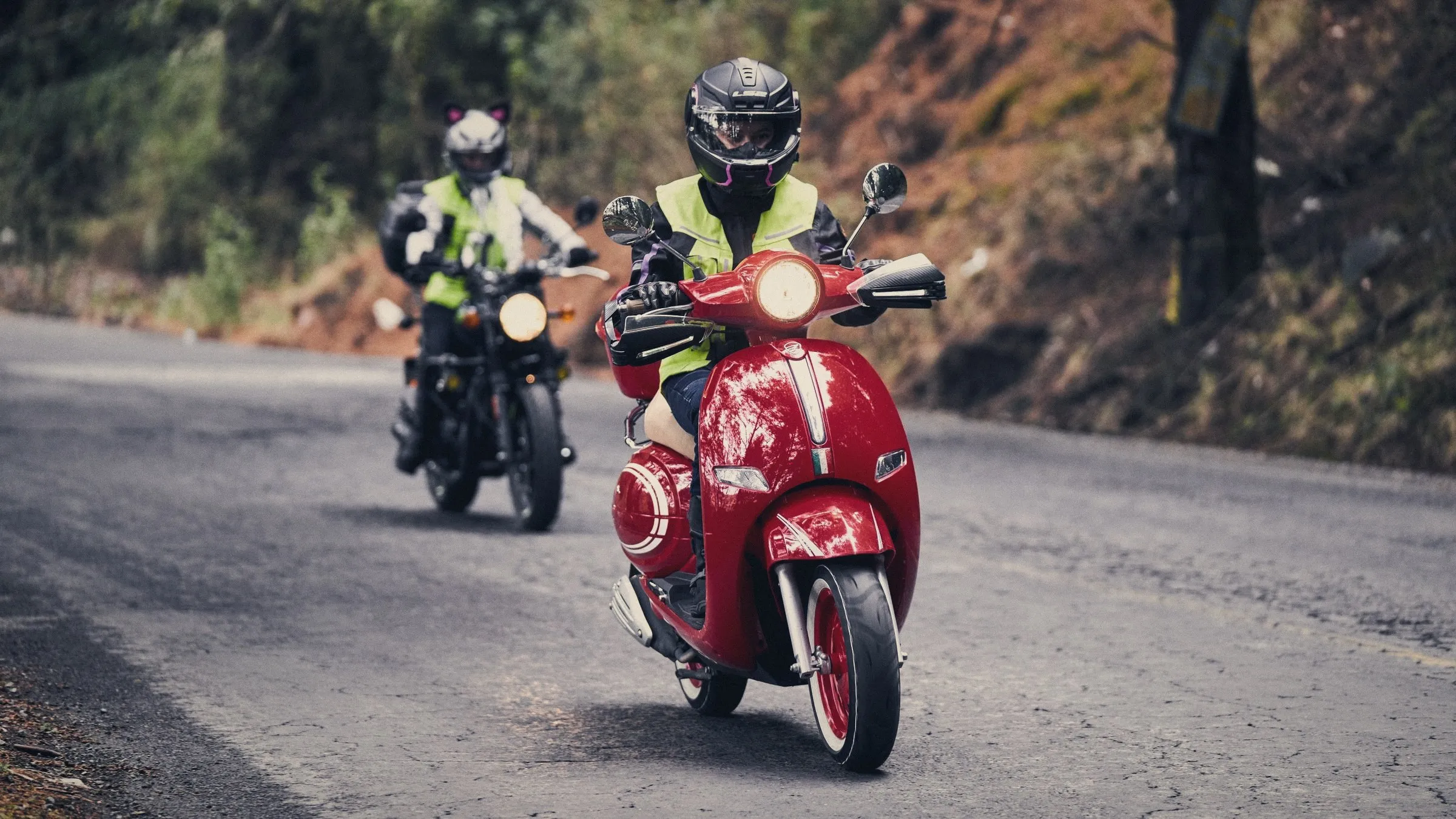 Dos motociclistas con casco y chaleco reflectivo en una carretera