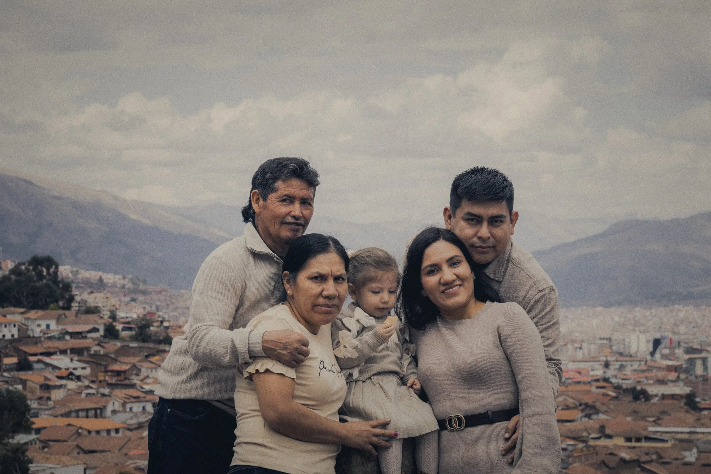 Familia de tres generaciones abrazada frente a la ciudad y las montañas